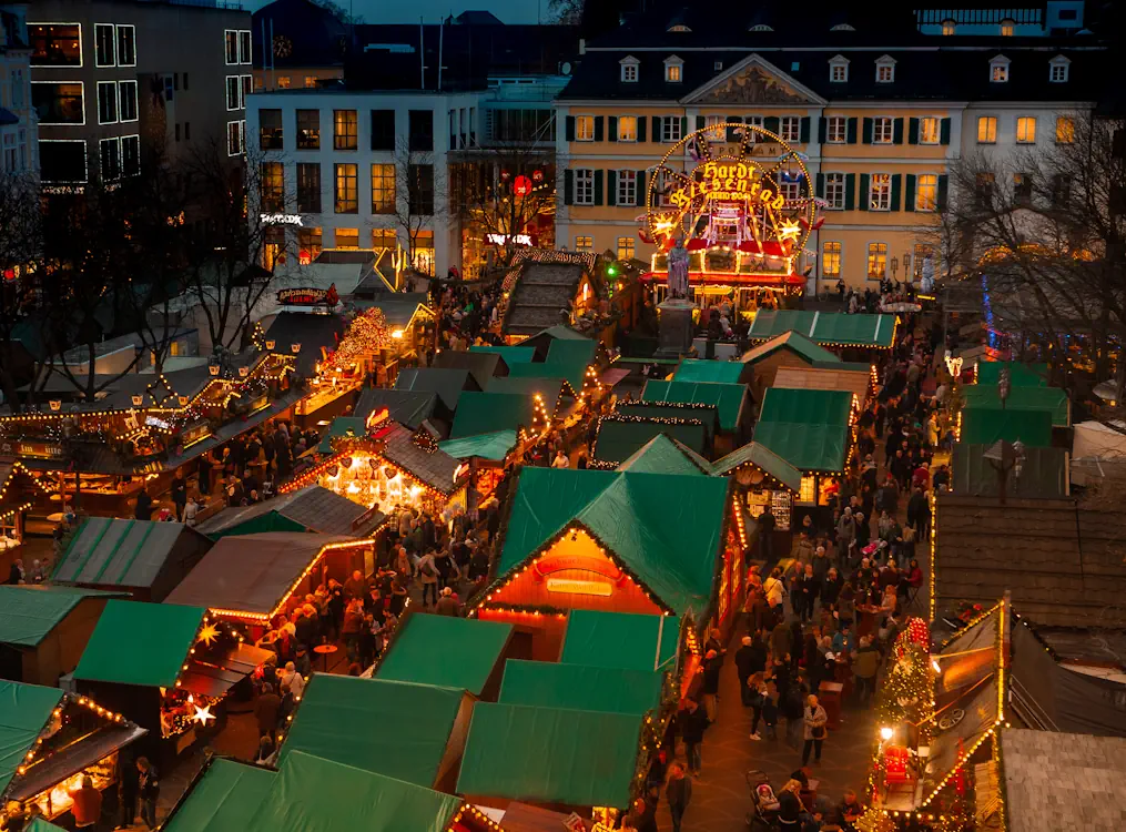 Eine Übersicht von Weihnachtsmärkten im Rheinland. Das Foto zeigt eine Luftaufnahme des Bonner Weihnachtsmarktes mit dem alten Postamt im Hintergrund
